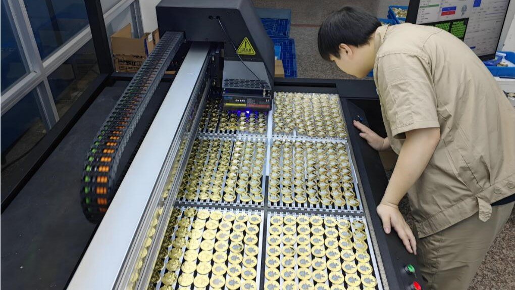 The worker is inspecting at a tray of enamel pins - featured image of grading enamel pins